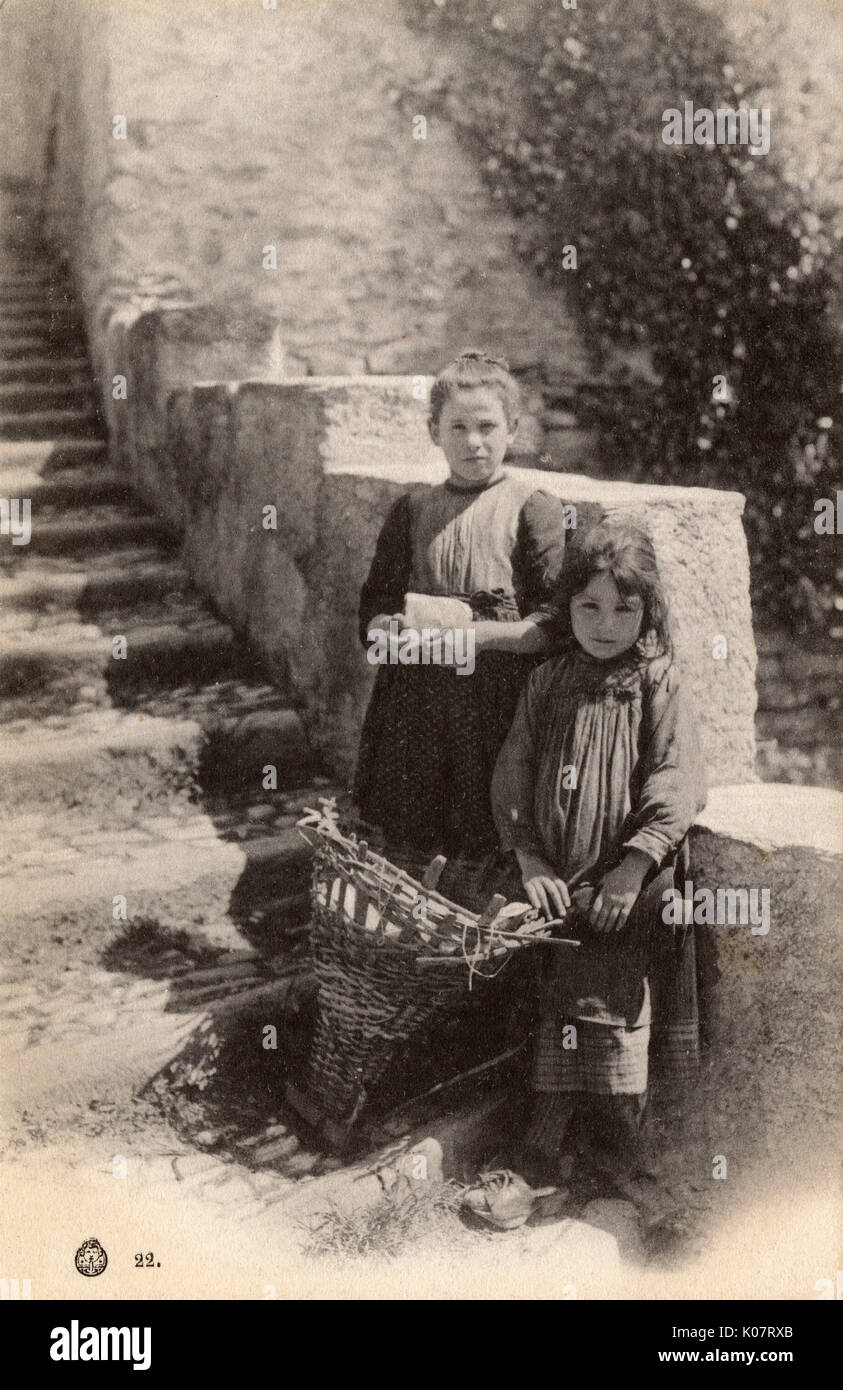 Two young girls from Como, Italy - the girl in the foreground has a traditional wicker backpack (used to carry hay) and is wearing clogs.     Date: circa 1910s Stock Photo