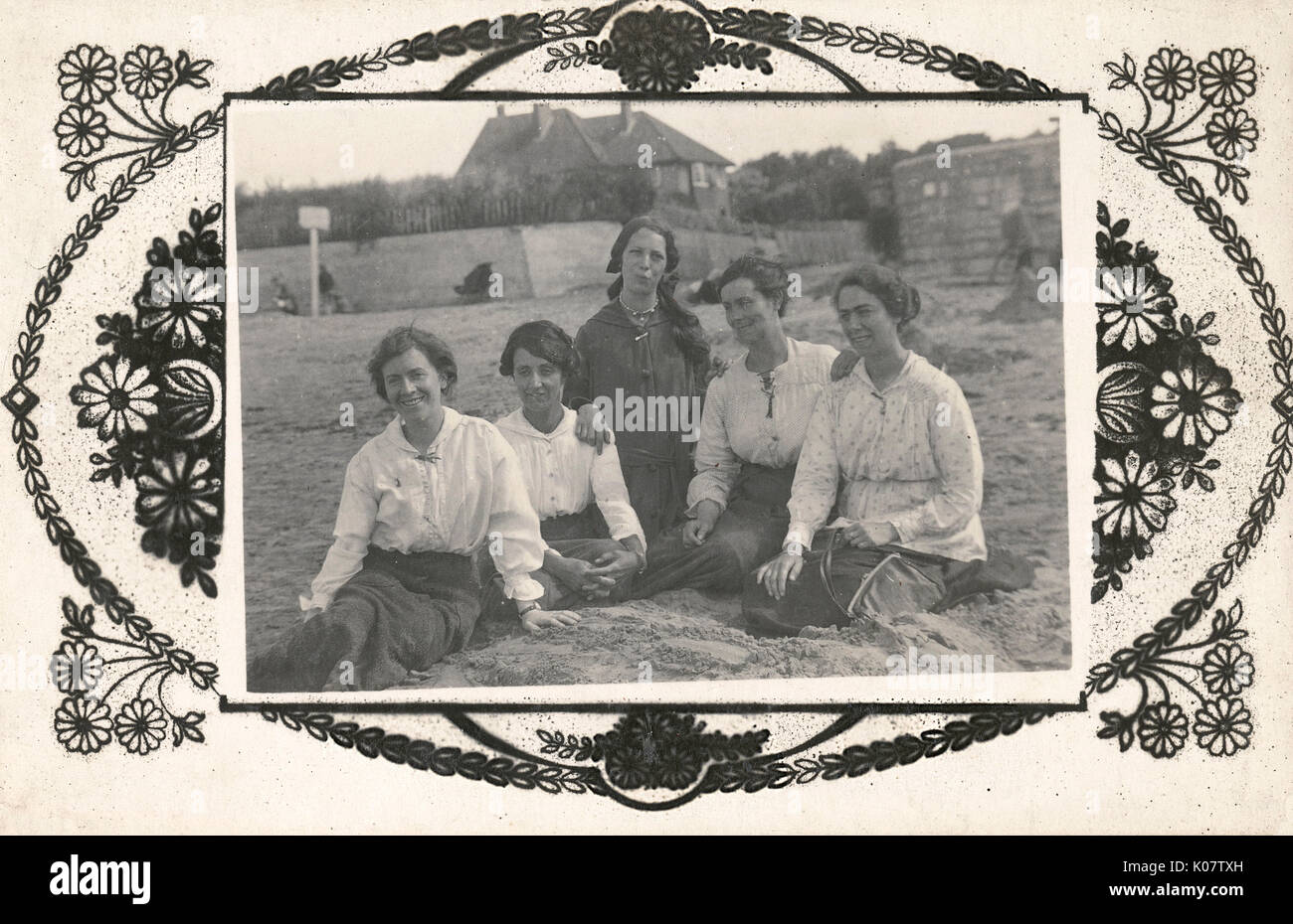 British country girls on a seaside excursion or vacation - sitting on a sandy beach     Date: circa 1908 Stock Photo
