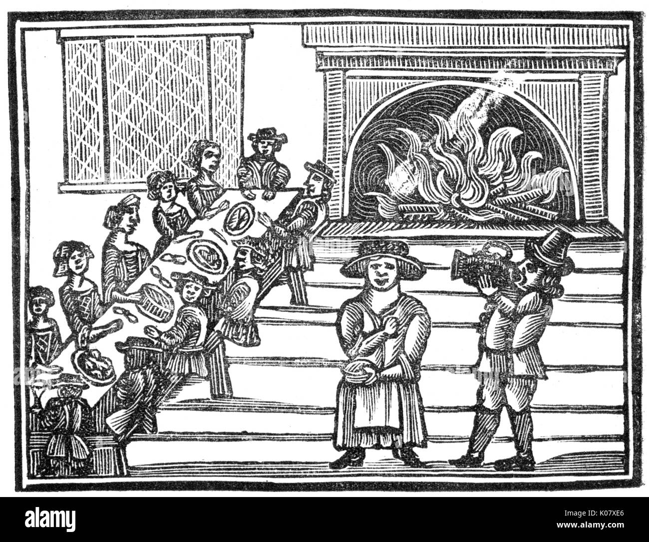 Feasting, c.1600. A party of people sit at a long table in a room with a roaring log fire and eat and drink their fill.     Date: C.1600 Stock Photo