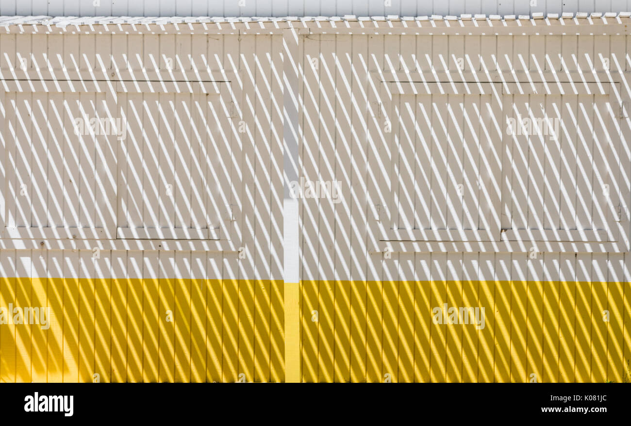 shadows on the front of a yellow and white painted facade of a farm stand in east hampton, ny Stock Photo