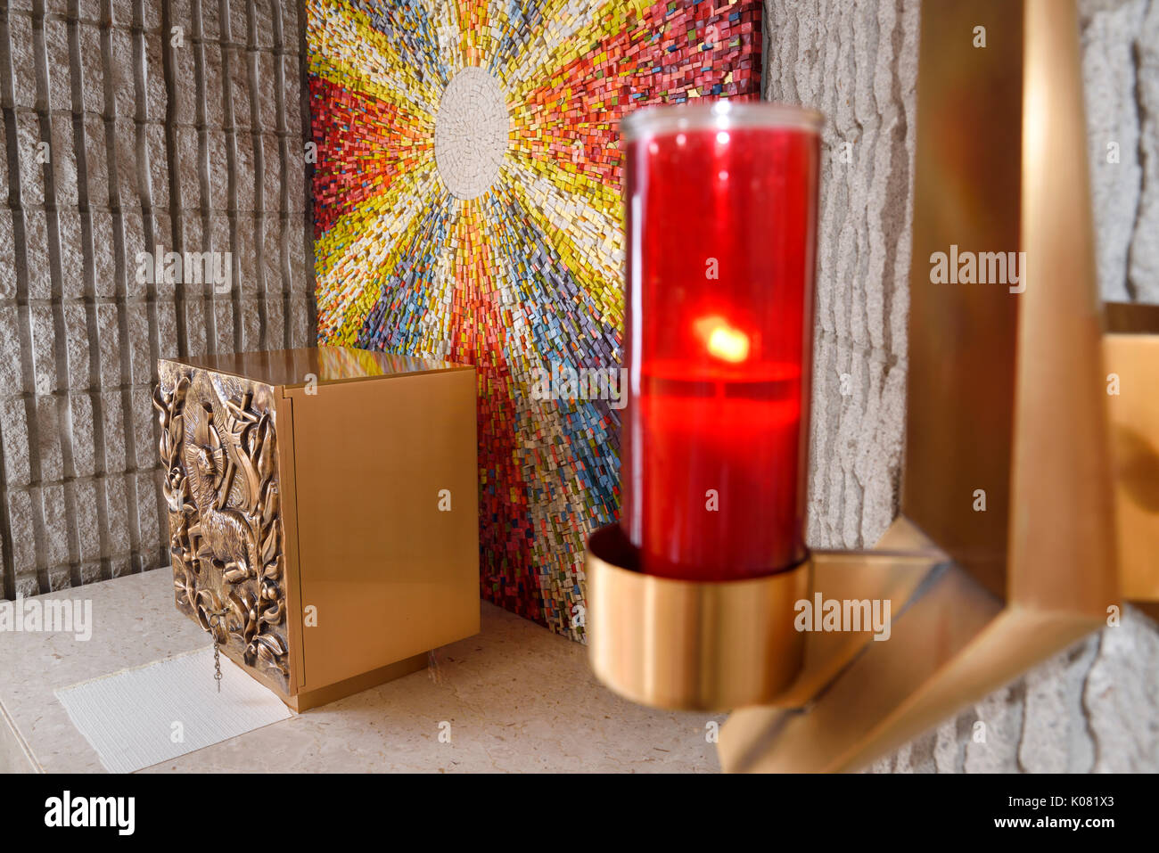 Red Sanctuary Lamp or Eternal Flame at the Tabernacle with bronze Lamb of God bas relief at side altar with sunburst mosaic in Catholic church Stock Photo