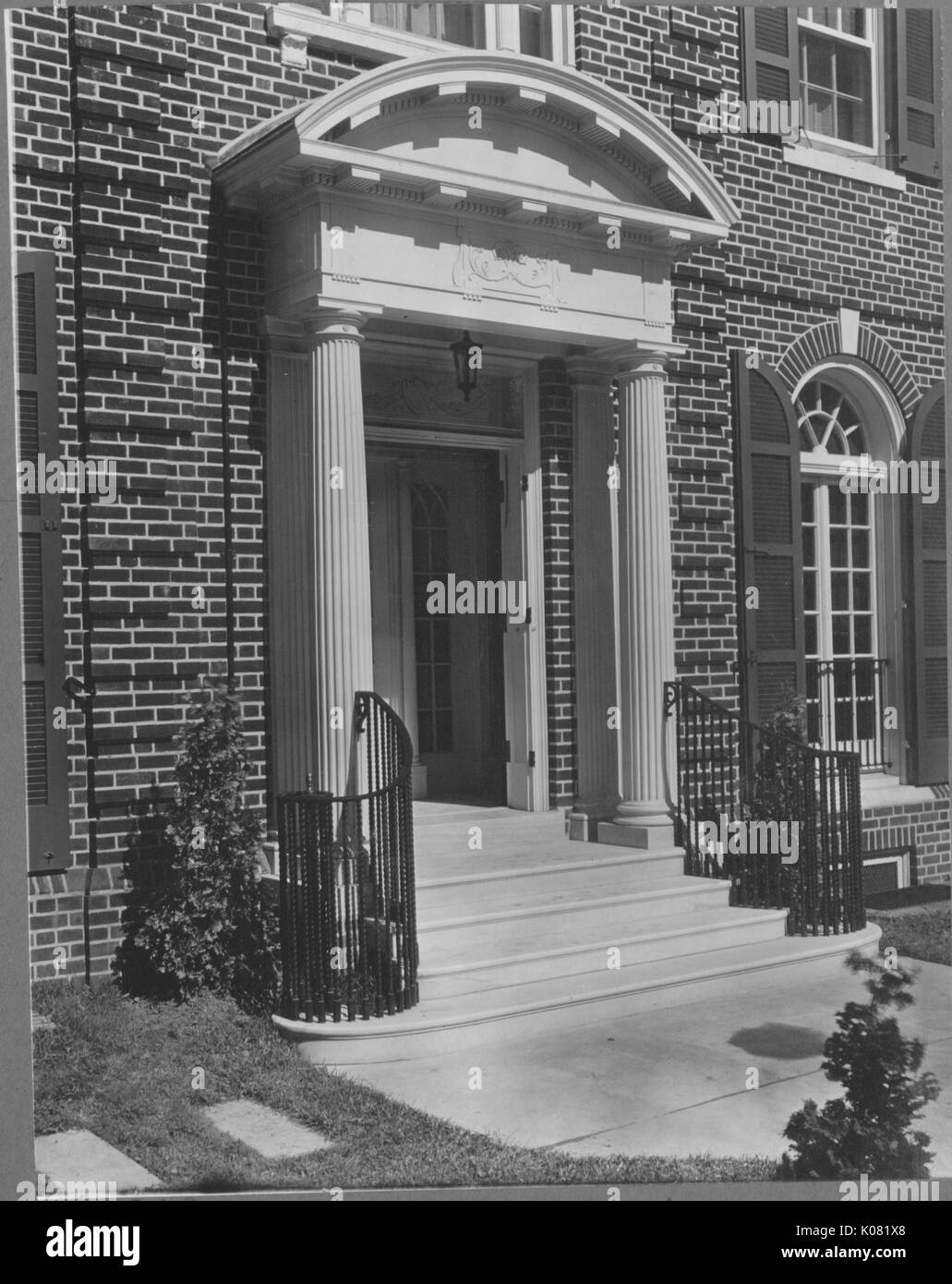 Picture of the front porch of a home in Roland Park home in Baltimore, with spiraling black railing, two Doric columns, and the house is of brick, United States, 1950. This image is from a series documenting the construction and sale of homes in the Roland Park/Guilford neighborhood of Baltimore, a streetcar suburb and one of the first planned communities in the United States. Stock Photo