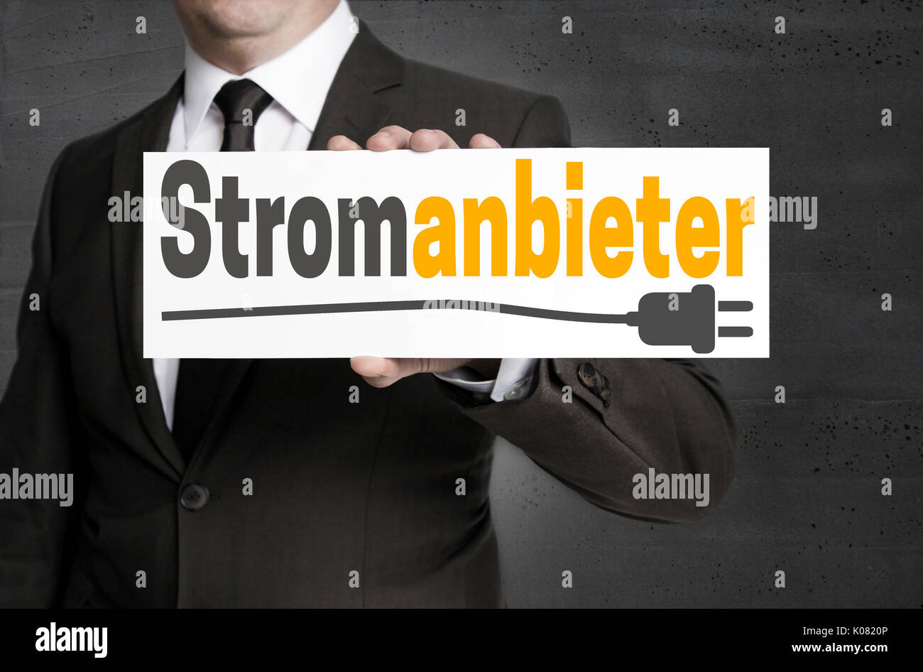 Stromanbieter (in german Electricity provider) sign is held by businessman. Stock Photo