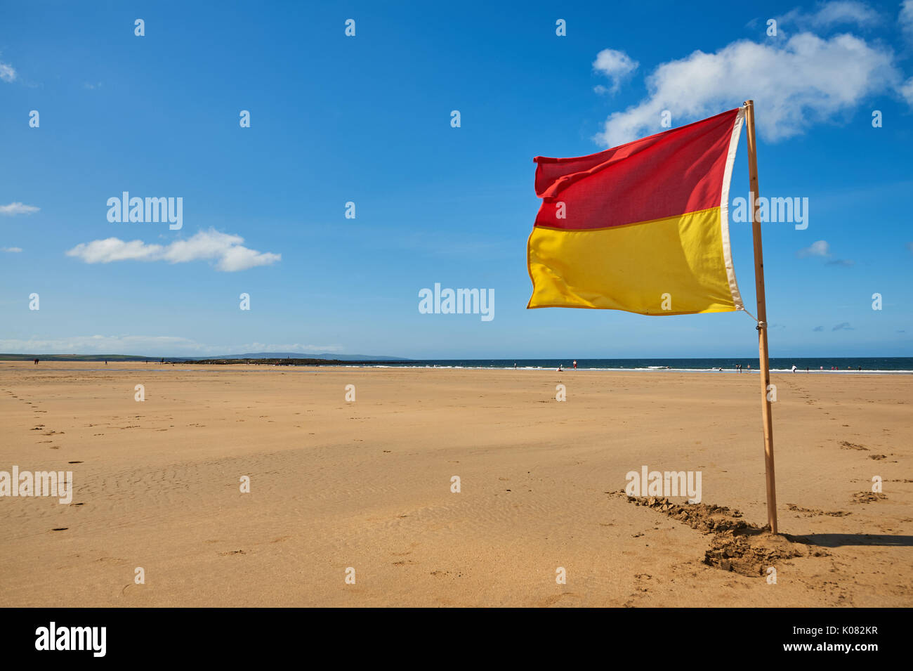 Red and yellow warning flag against a blue sky advising swimmers on the beach at Ballybunion, County Kerry Ireland Stock Photo