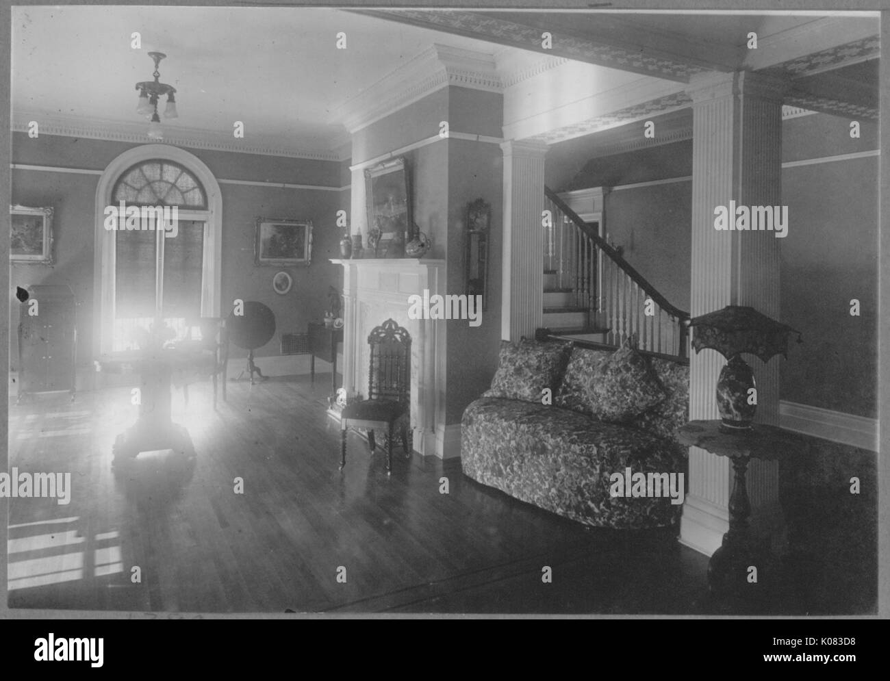 Sitting room of a house, wooden floors, small patterned couch, small decorative tables; Roland Park/Guilford, 1910. This image is from a series documenting the construction and sale of homes in the Roland Park/Guilford neighborhood of Baltimore, a streetcar suburb and one of the first planned communities in the United States. Stock Photo