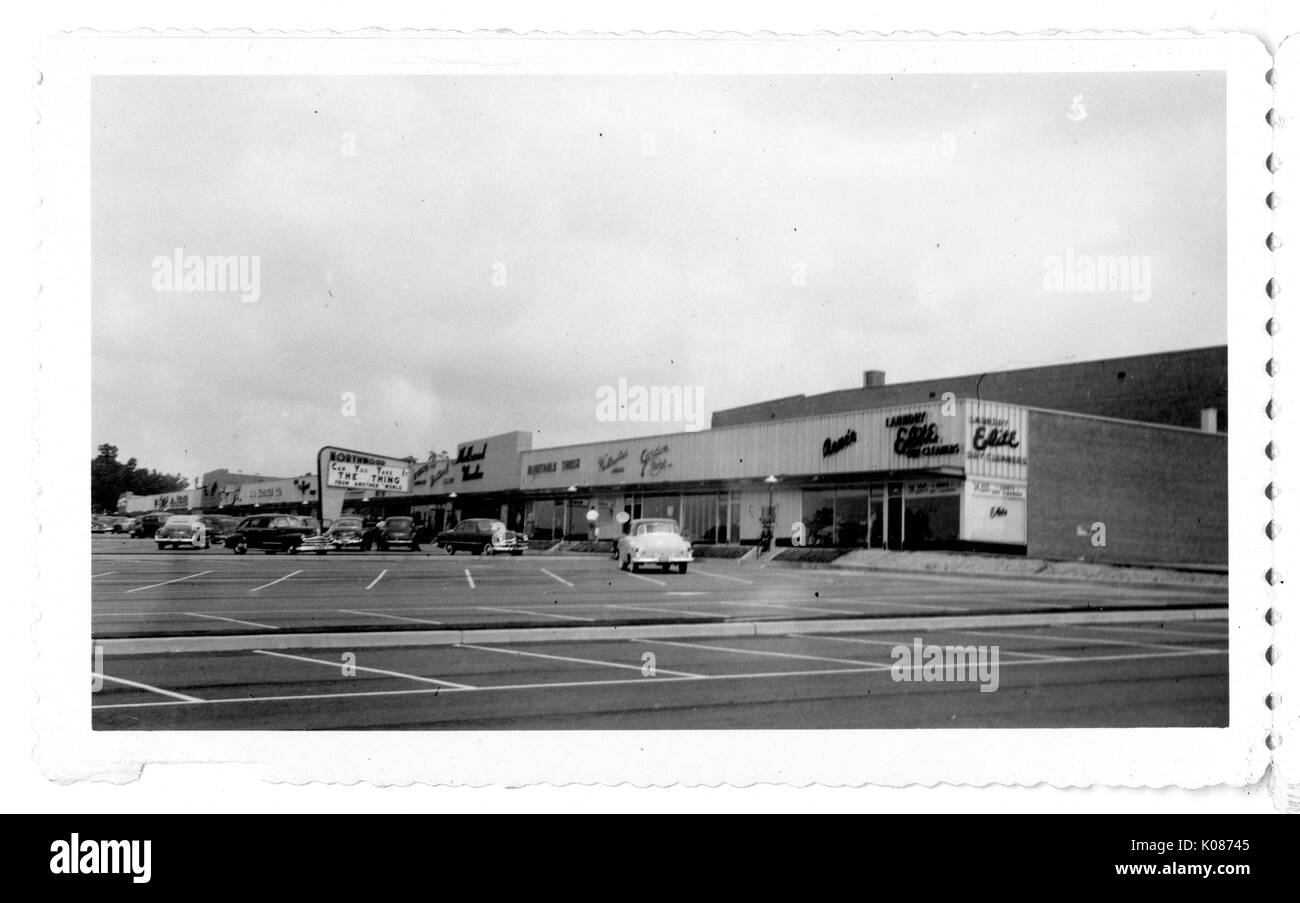 Parking lot of Northwood Shopping Center with cars and shops with signs, Baltimore, Maryland