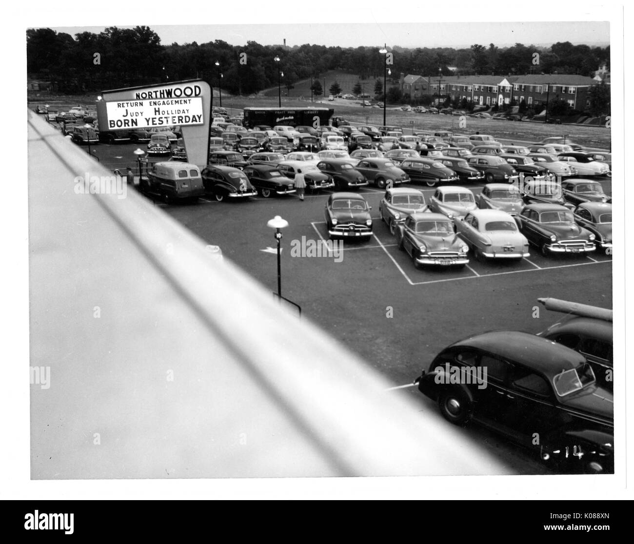 View of a packed parking lot from the roof of the Northwood Shopping Center, across the street from the center and parking lot are brick row homes, the center's sign is advertising 'RETURN ENGAGEMENT, JUDY HOLIDAY, BORN YESTERDAY', Baltimore, Maryland, 1951. Stock Photo