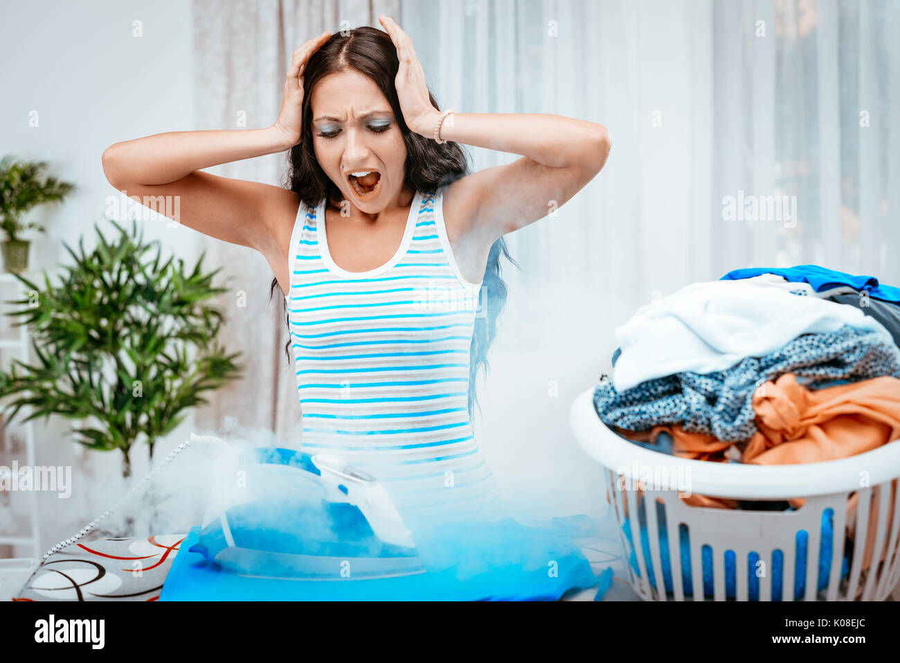 Worried young housewife ironing clothes. Stock Photo