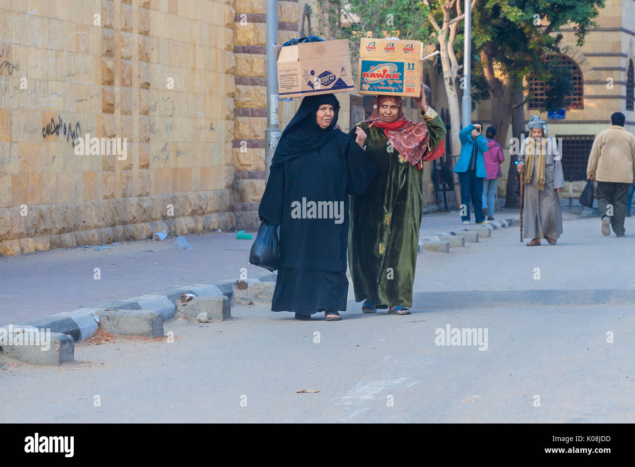 Women carry on their heads filled cartons, egyptian people on streets in Cairo Stock Photo