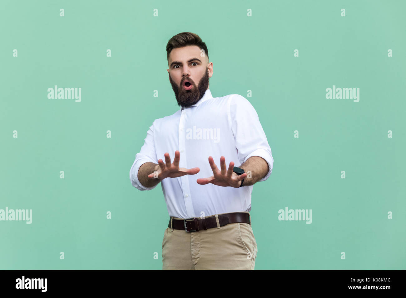 Not me! Stylish bearded man with shocked. Businessman having amazed face, looking at camera. Indoor, studio shot, light green background Stock Photo