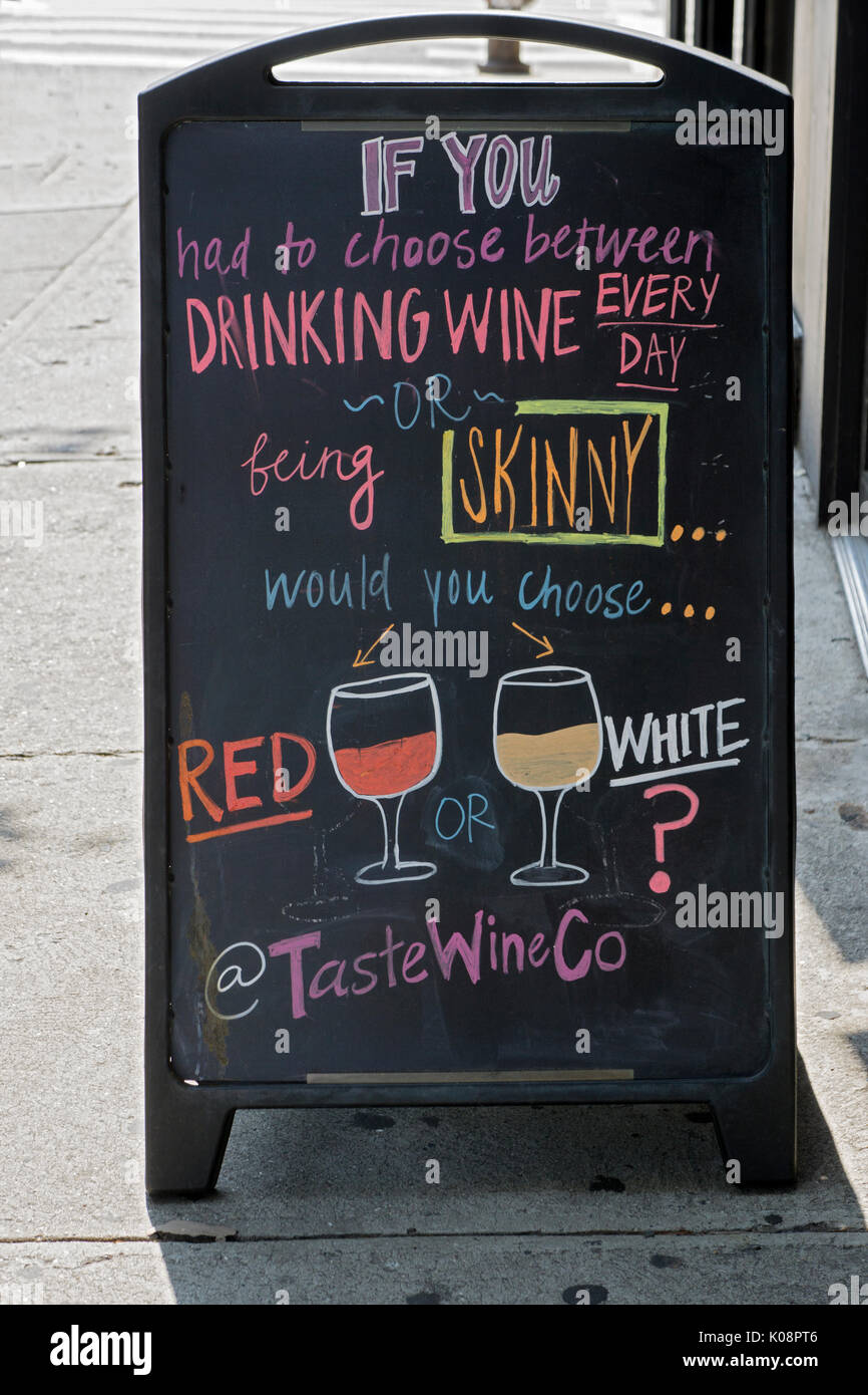 A funny sign outside the Taste Wine Co. liquor store on Third Avenue in the East Village extolling the decision of drinking wine versus dieting. Stock Photo