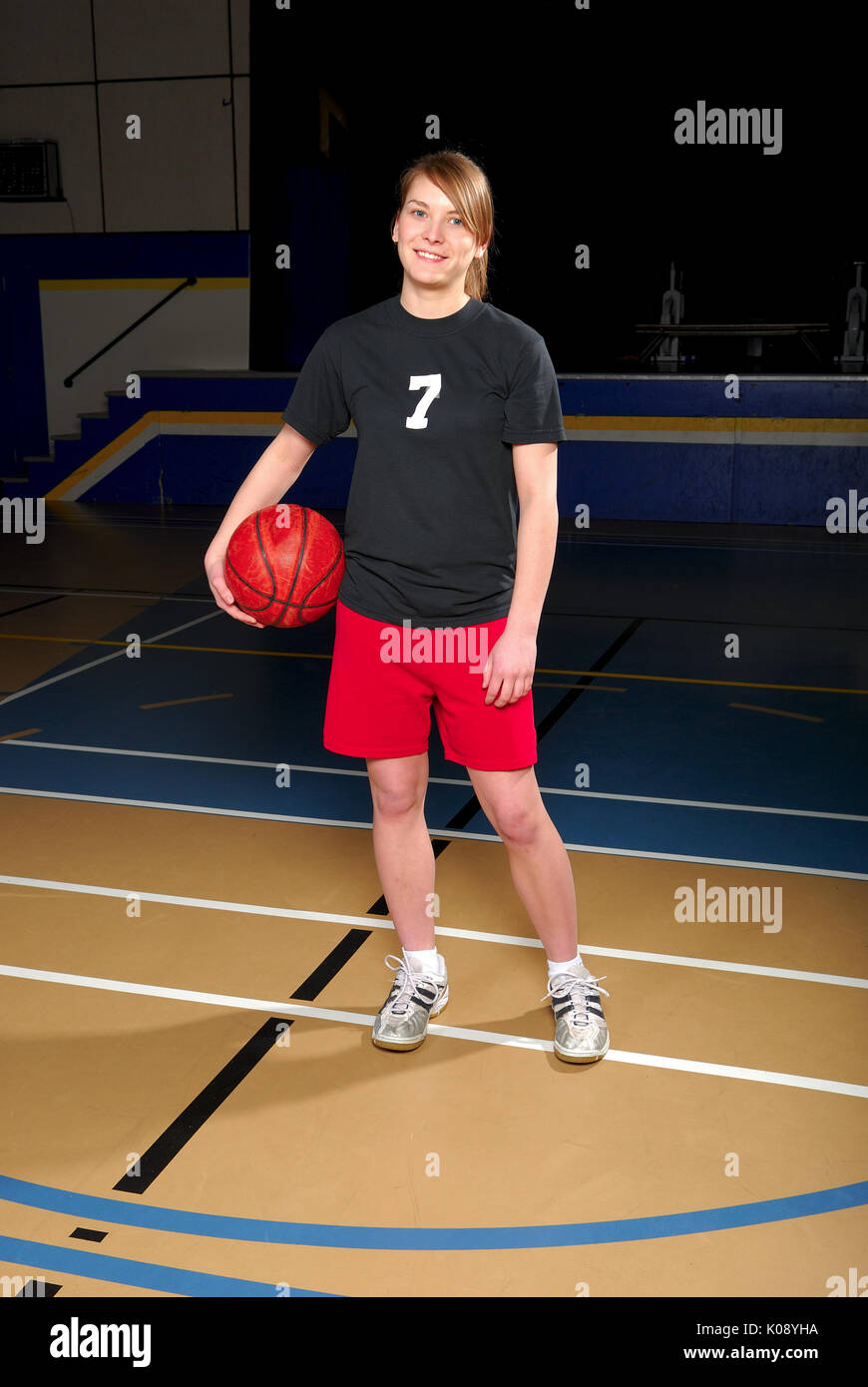 A female teenage basketball player in school gymnasium. Stock Photo