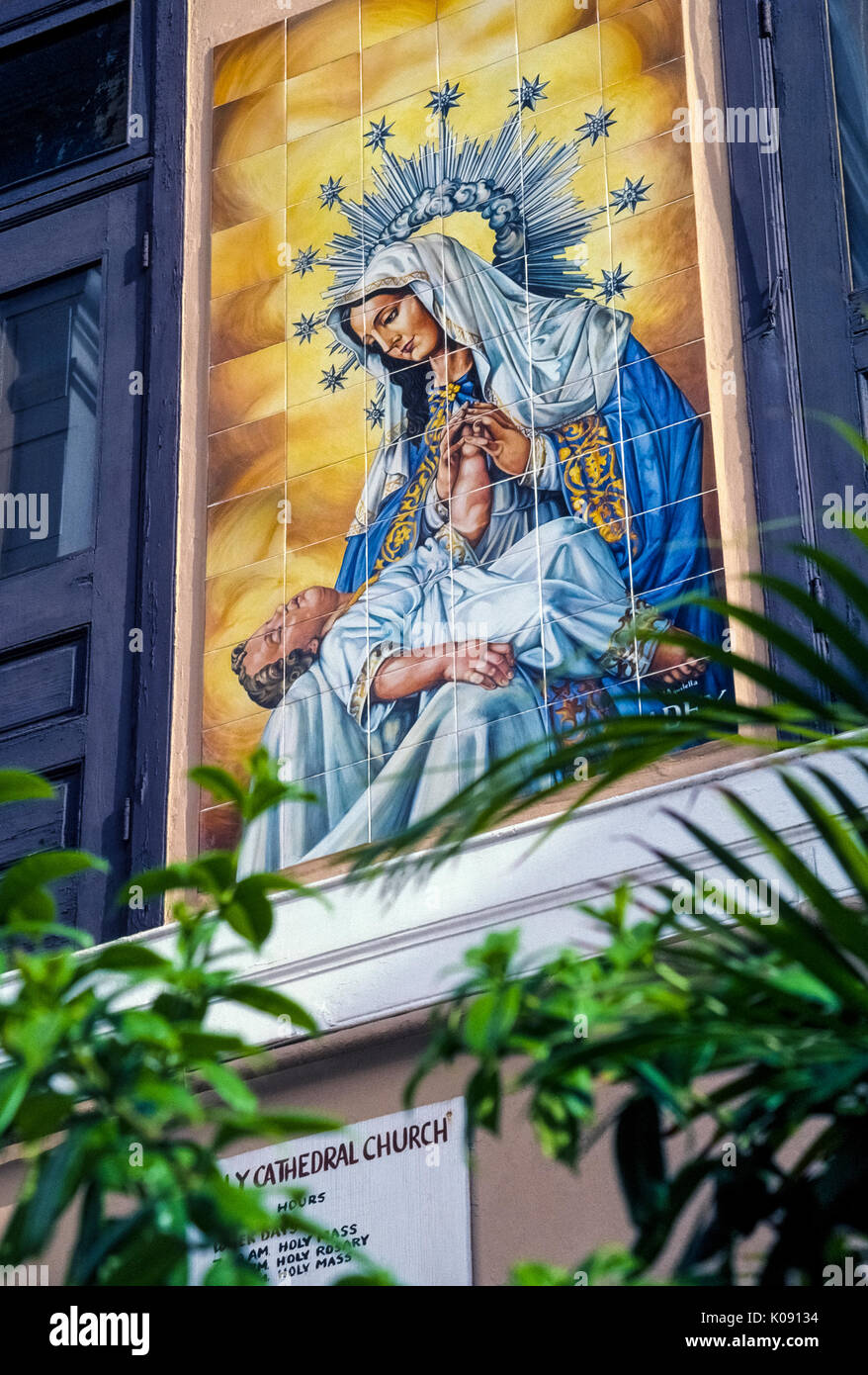 This religious artwork of colorful ceramic tiles showing the Virgin Mary holding baby Jesus is on the exterior of the Cathedral of San Juan Bautista in historic Old San Juan in the Commonwealth of Puerto Rico (PR), an unincorporated territory of the United States in the Caribbean Sea. The cathedral was built in the early 1500s and holds the marble tomb of Ponce de Leon, the famed Spanish explorer who founded San Juan. Stock Photo