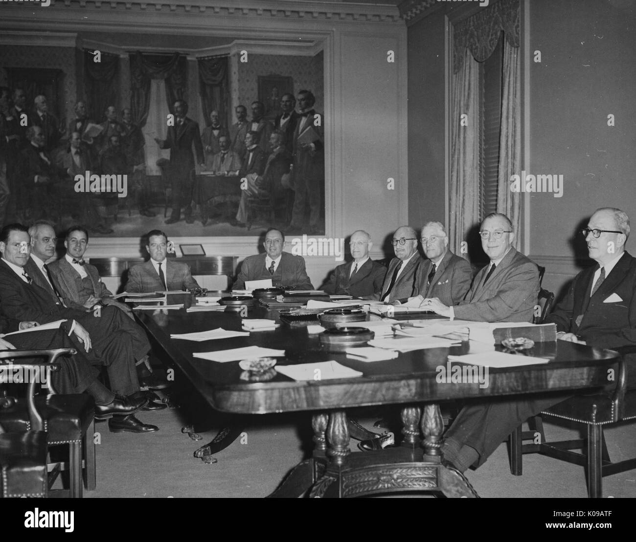Landscape shot of ten men sitting around a wooden table, upon which papers are scattered; the Executive Board of Trustees with Milton S Eisenhower, December 14, 1959. Stock Photo