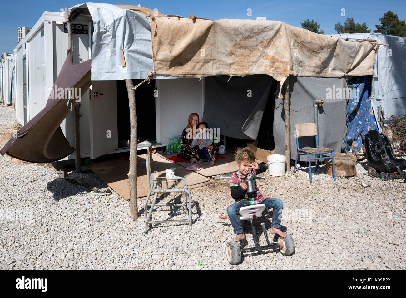 Mother and children outside their prefabricated shelter in the Ritsona