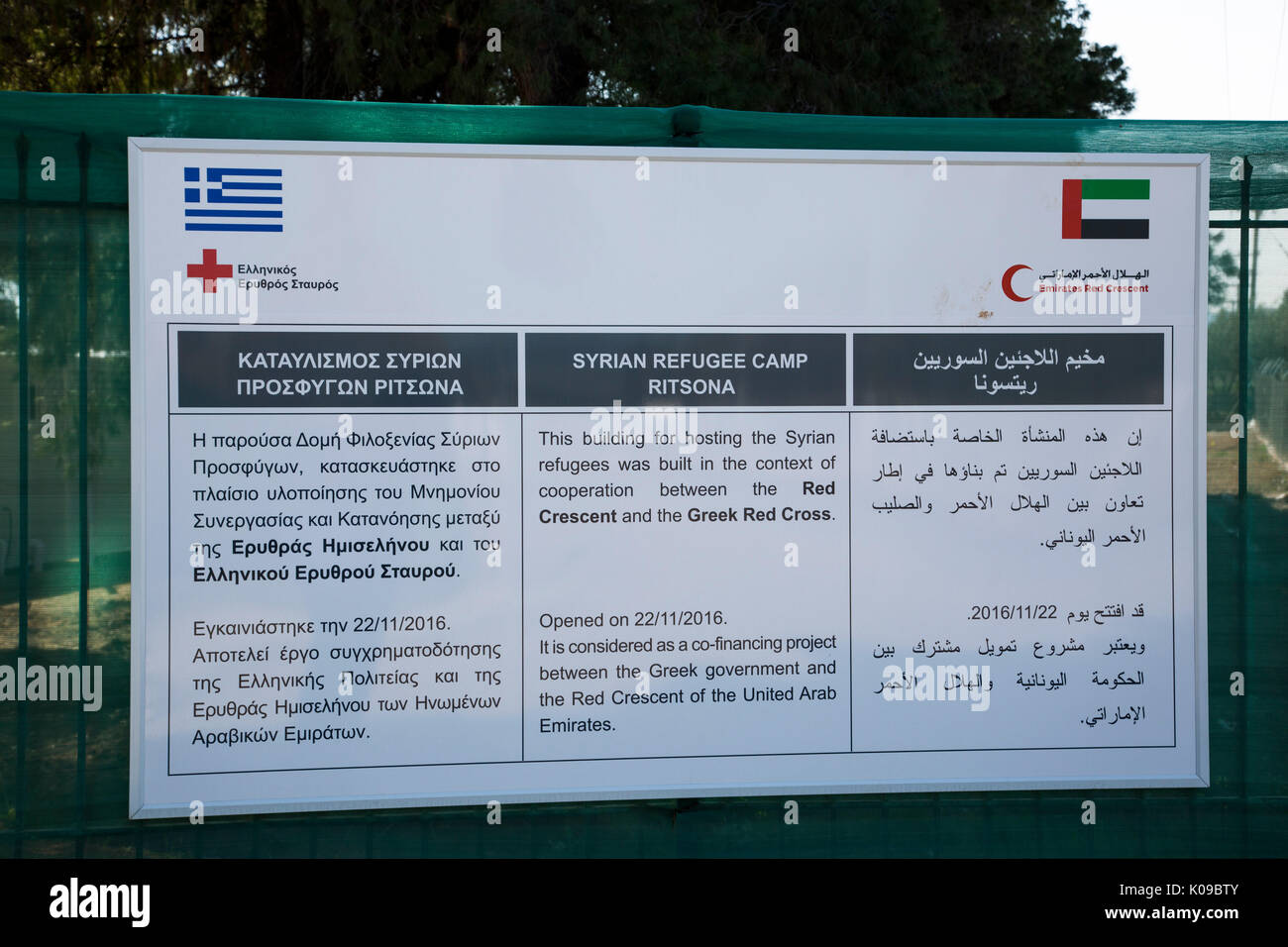 A sign at the entrance to Ritsona Refugee Camp in Greek, English and Arabic tells of cooperation of Greek Red Cross and Emirates Red Crescent. Stock Photo