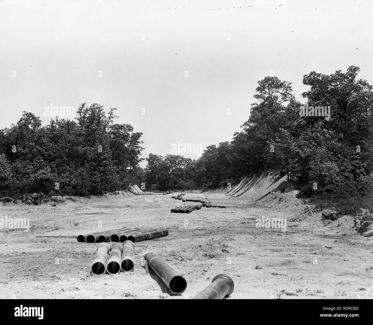 Northwood neighborhood land under construction, there are large pipes scattered on the dirt, there are trees and bushes in the background that are bordering the land, United States, 1950. Stock Photo