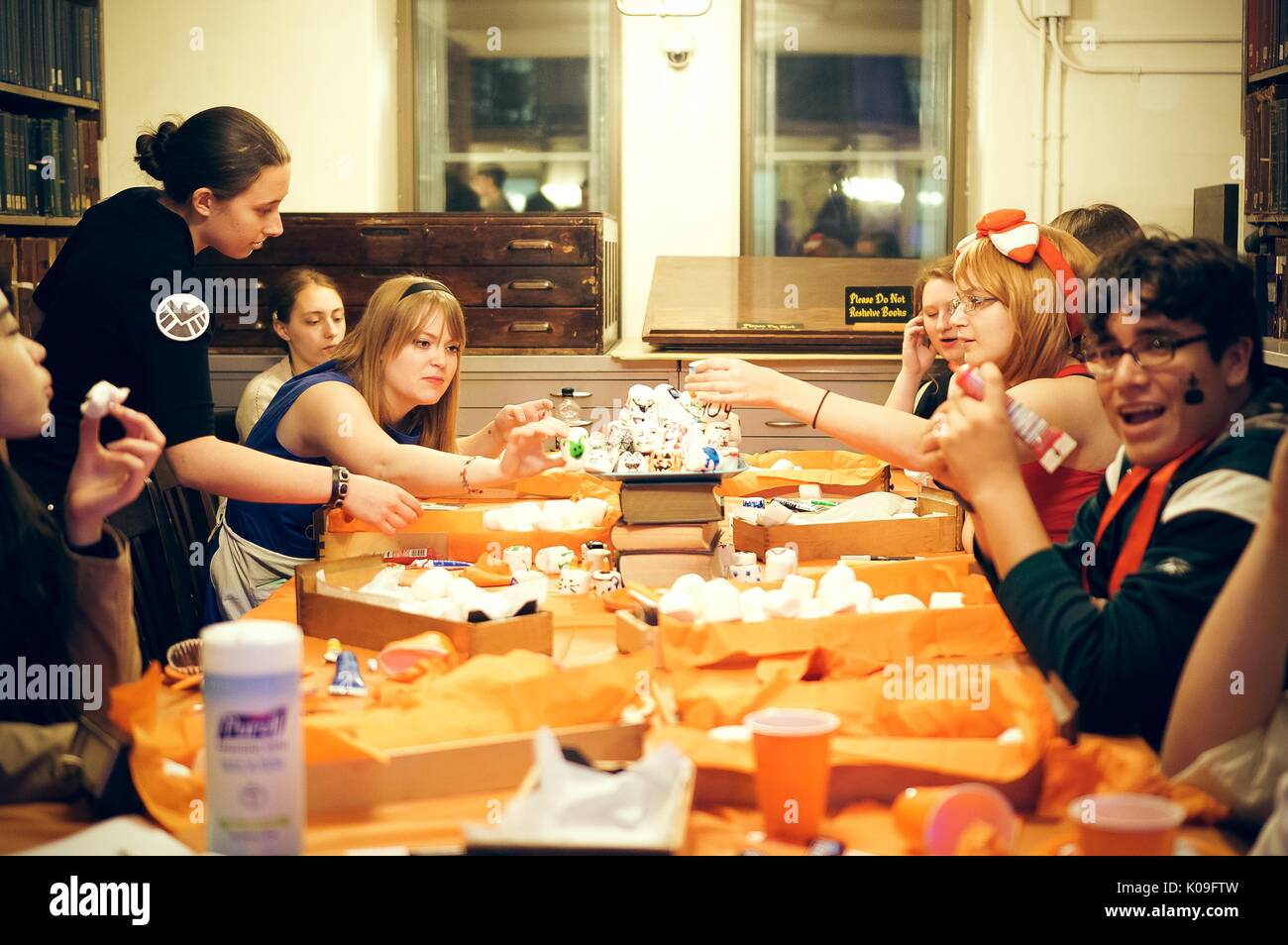 College students are sitting around a table covered in decorating tools and large marshmallows, the students are all in different costumes and are working to decorate the marshmallows, 2015. Courtesy Eric Chen. Stock Photo