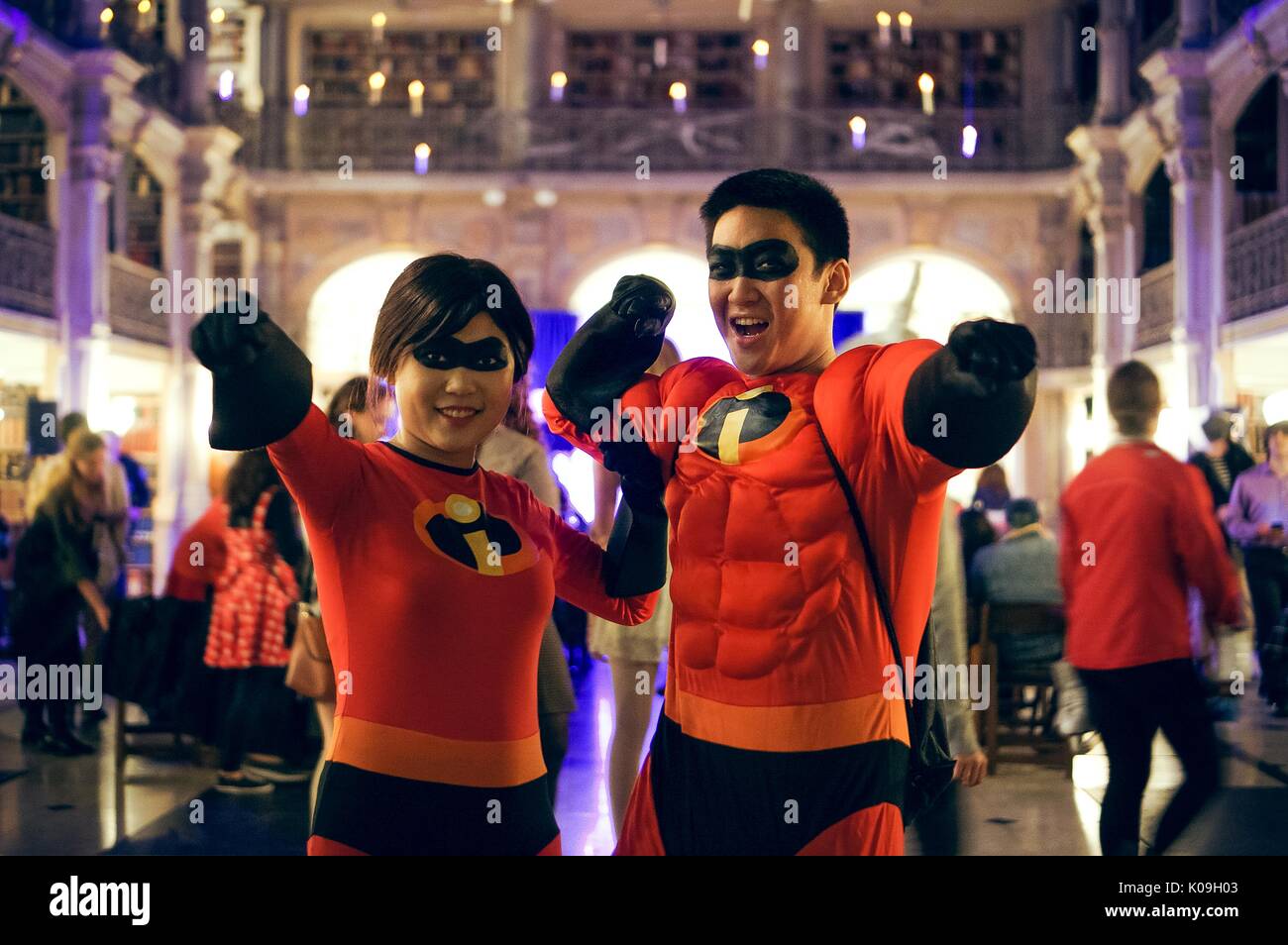 Two college students, a male and female in a couple, point and pose in matching costumes featuring characters from the film 'The Incredibles', on Halloween at Johns Hopkins University's George Peabody Library, 2015. Courtesy Eric Chen. Stock Photo