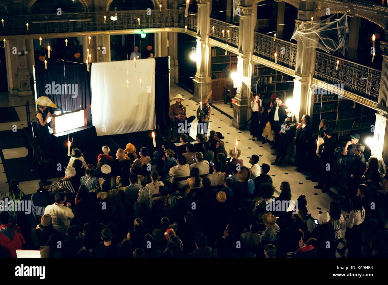 View from an upper level of the Peabody Library of the audience, the stage, the musicians, and shadow puppet performers, during Halloween at Johns Hopkins University's George Peabody Library, 2015. Courtesy Eric Chen. Stock Photo