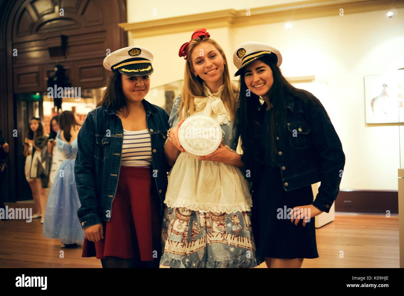 Three college students pose for a picture, two girls on the ends are dressed as sailors with sailor hats and the girl in the middle is dressed as Alice in Wonderland and is holding a clock, 2015. Courtesy Eric Chen. Stock Photo