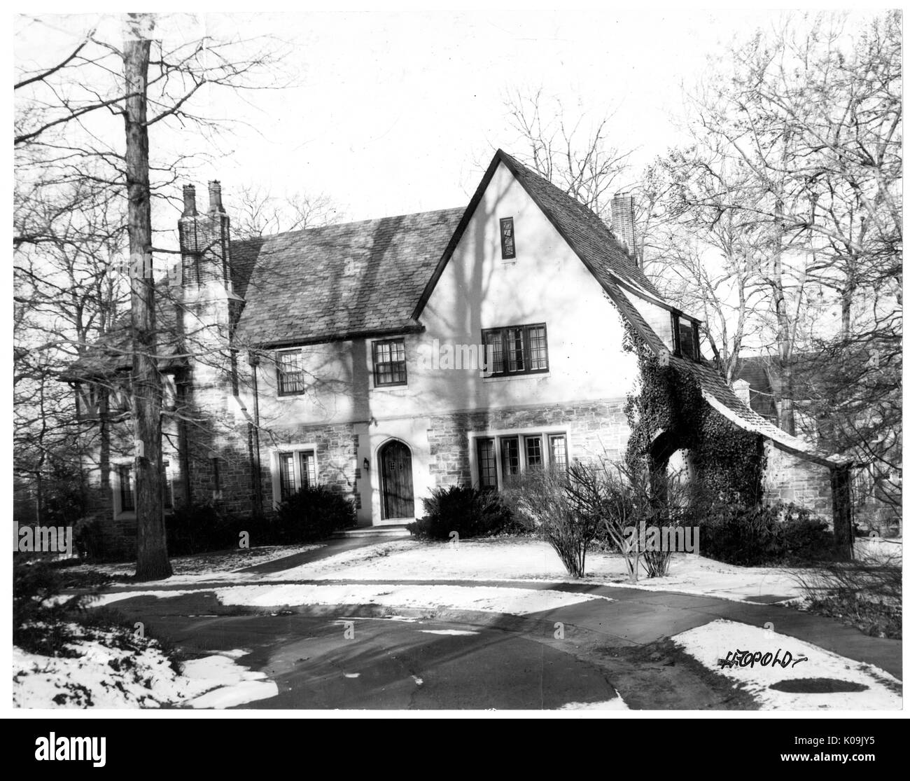 Front angle view of a single family house near Guilford, part of the house is made out of stone and the house is at least two stories, there is chimney that scales the front of the house, Baltimore, Maryland, 1910. This image is from a series documenting the construction and sale of homes in the Roland Park/Guilford neighborhood of Baltimore, a streetcar suburb and one of the first planned communities in the United States. The neighborhood was segregated, and is considered an early example of the enforcement of racial segregation through the use of restricted covenants. Stock Photo