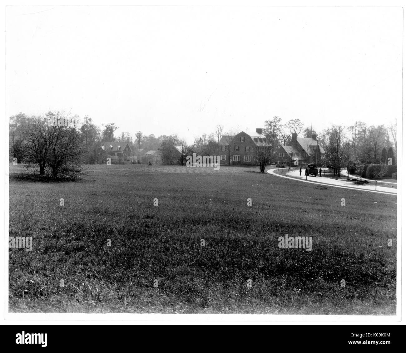 A large open area of grass lays in front of a large house near Guilford, the house is in the background and there is a long pathway that leads toward it, there are trees on the property, most of the trees are near the house, Baltimore, Maryland, 1910. This image is from a series documenting the construction and sale of homes in the Roland Park/Guilford neighborhood of Baltimore, a streetcar suburb and one of the first planned communities in the United States. The neighborhood was segregated, and is considered an early example of the enforcement of racial segregation through the use of restrict Stock Photo