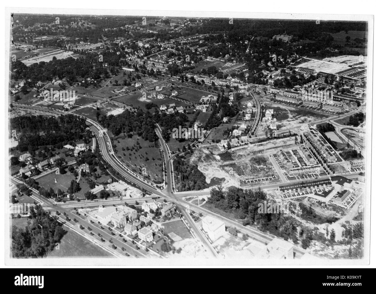 Aerial view of roads and highways intersecting, with neighborhoods to the left, and grassy areas with trees toward the back, Roland Park/Guilford, Baltimore, Maryland, 1910. This image is from a series documenting the construction and sale of homes in the Roland Park/Guilford neighborhood of Baltimore, a streetcar suburb and one of the first planned communities in the United States. The neighborhood was segregated, and is considered an early example of the enforcement of racial segregation through the use of restricted covenants. Stock Photo