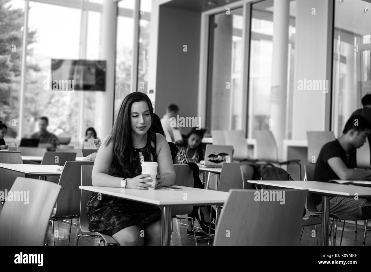 Female Johns Hopkins college student wearing dress enjoying coffee at Brody Cafe, a cafe in Brody Learning Commons, a study area for students, 2015. Courtesy Eric Chen. Stock Photo