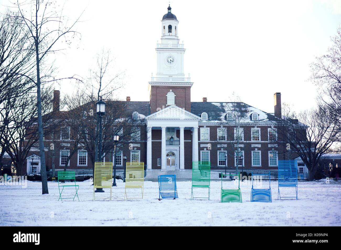 Several multicolored lawn chairs are lined up in front of Gilman Hall on the snowy Keyser quadrangle on the Homewood campus of the Johns Hopkins University in Baltimore, Maryland, 2015. Courtesy Eric Chen. Stock Photo