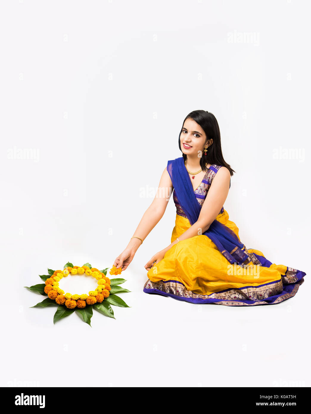 Indian woman or young girl making floral or flower rangoli for diwali or onam, isolated over white background Stock Photo