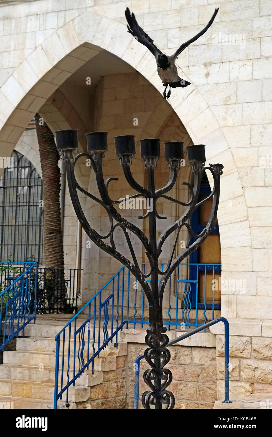 Crow flying over the Jewish Menorah placed outside the Conegliano Veneto Synagogue and the Italian Jewish Museum in Hilel street West Jerusalem Israel Stock Photo