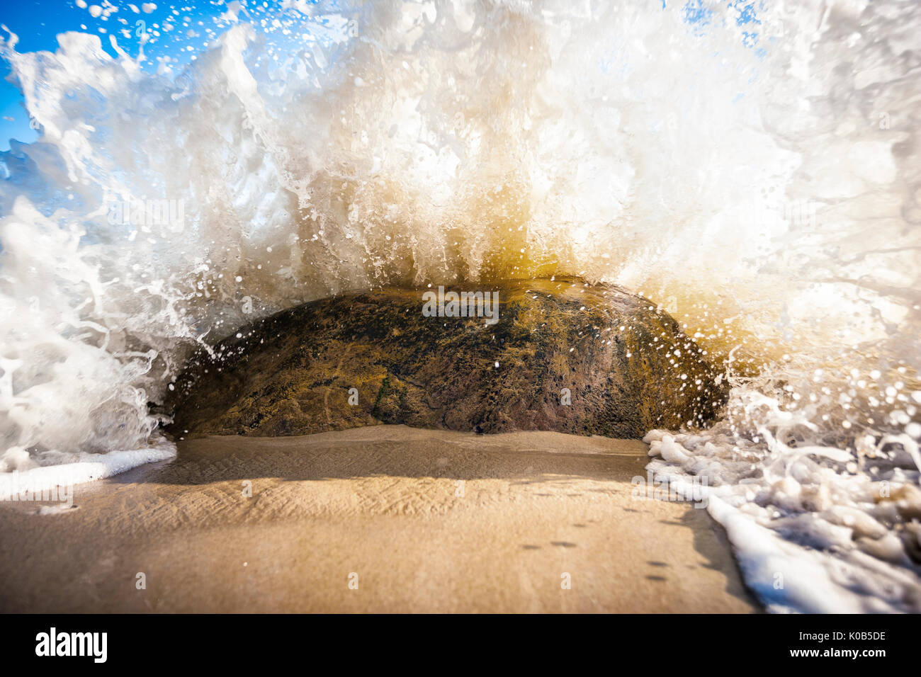 Wave splash rock on the sand beach Stock Photo