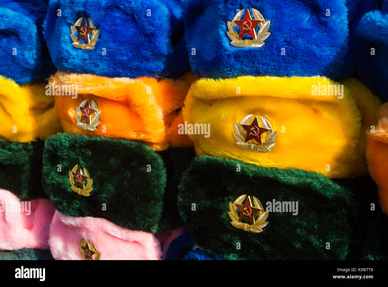 Rows of russian winter hats of different colors with army emblems at the street market at Old Arbat street, iconic popular souvenir from Russia. Stock Photo