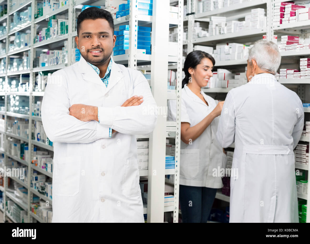 Young Chemist Standing Arms Crossed While Colleagues Checking St Stock