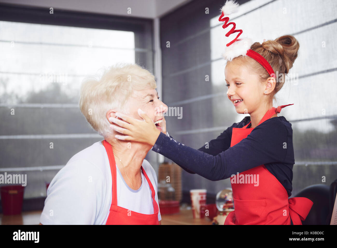 Granddaughter rubbing flour on grandmother's face Stock Photo