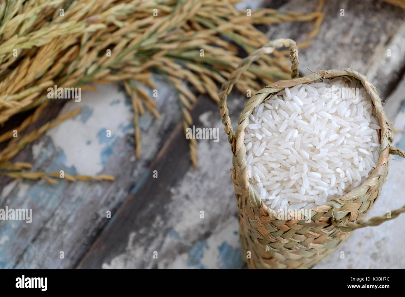 Close up of paddy grain and rice seed on wooden background, sheaf of rice in yellow and basket of grains Stock Photo