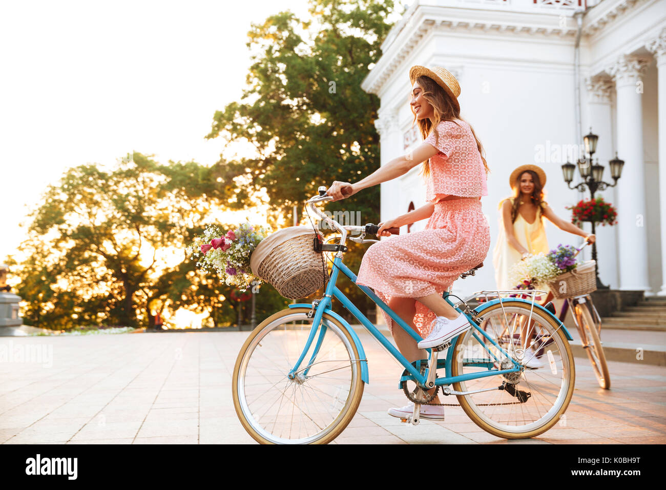Two pretty smiling girls on a bicycle ride together outdoors Stock Photo