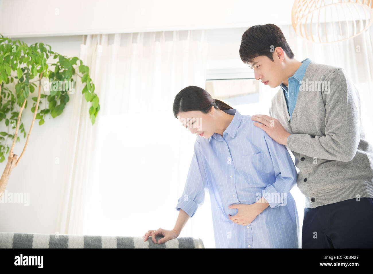 Pregnant wife feeling pain and her loving husband worried Stock Photo