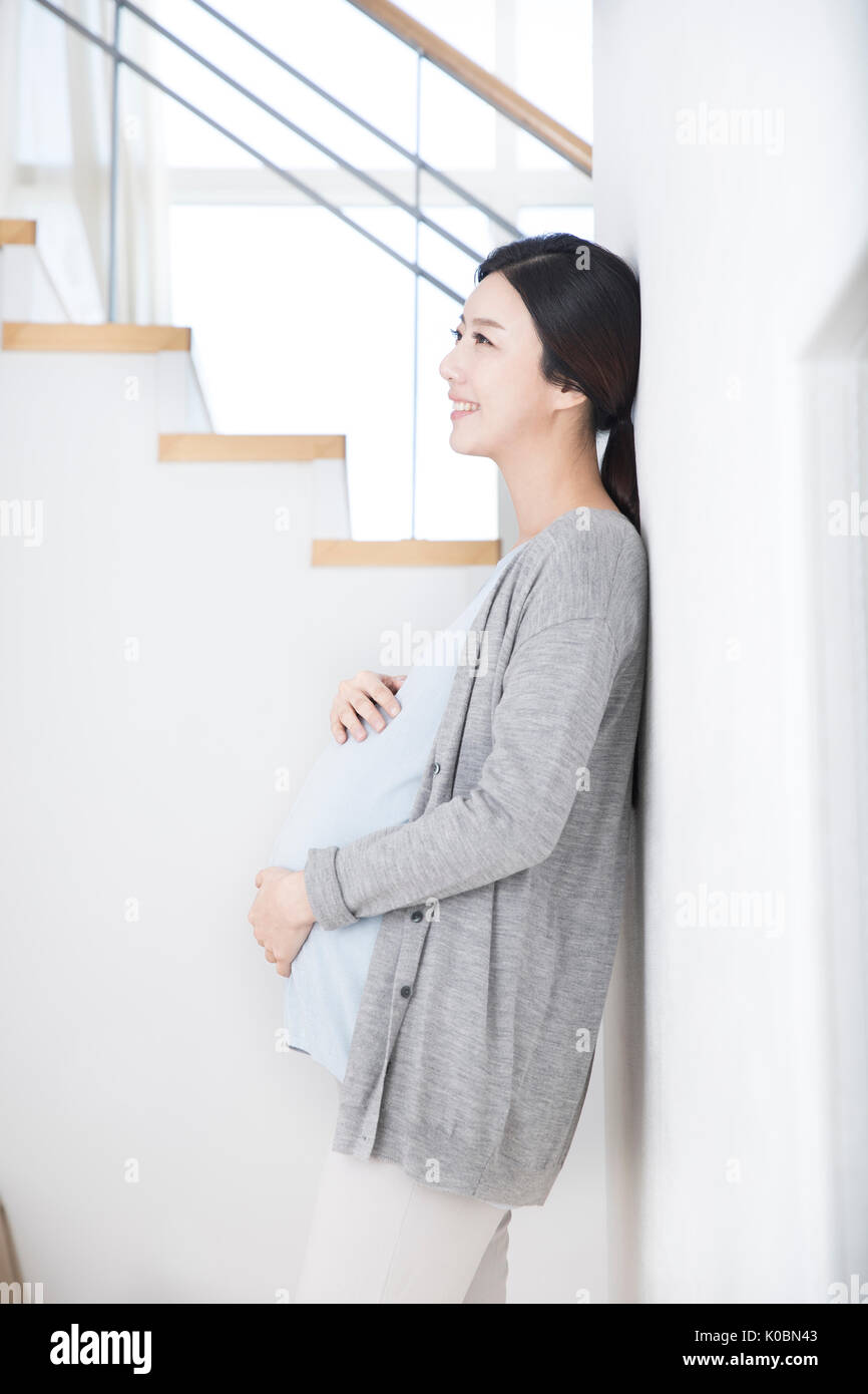 Side view of smiling pregnant woman leaning touching her belly Stock Photo