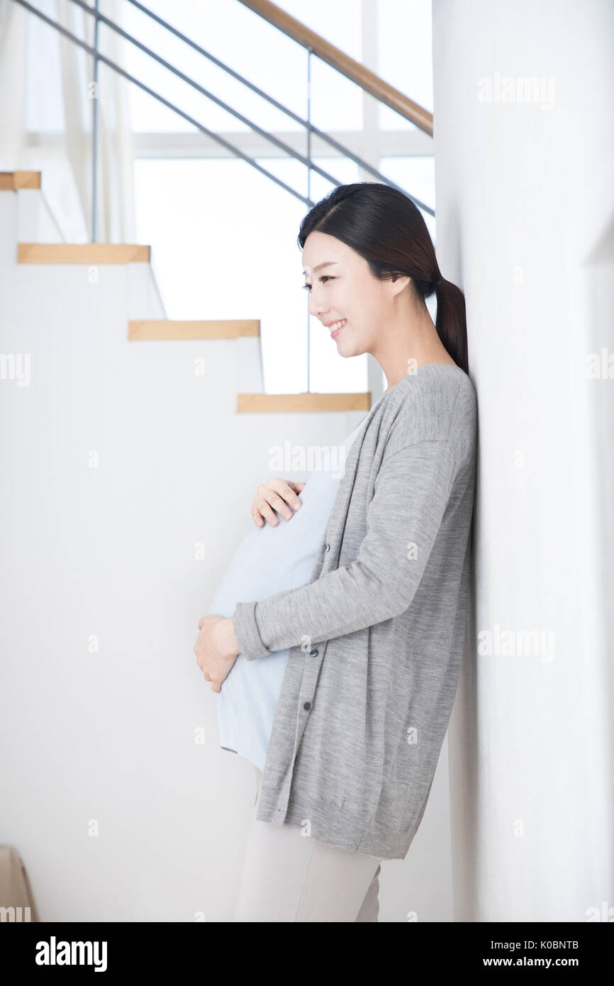 Side view of smiling pregnant woman touching her belly Stock Photo