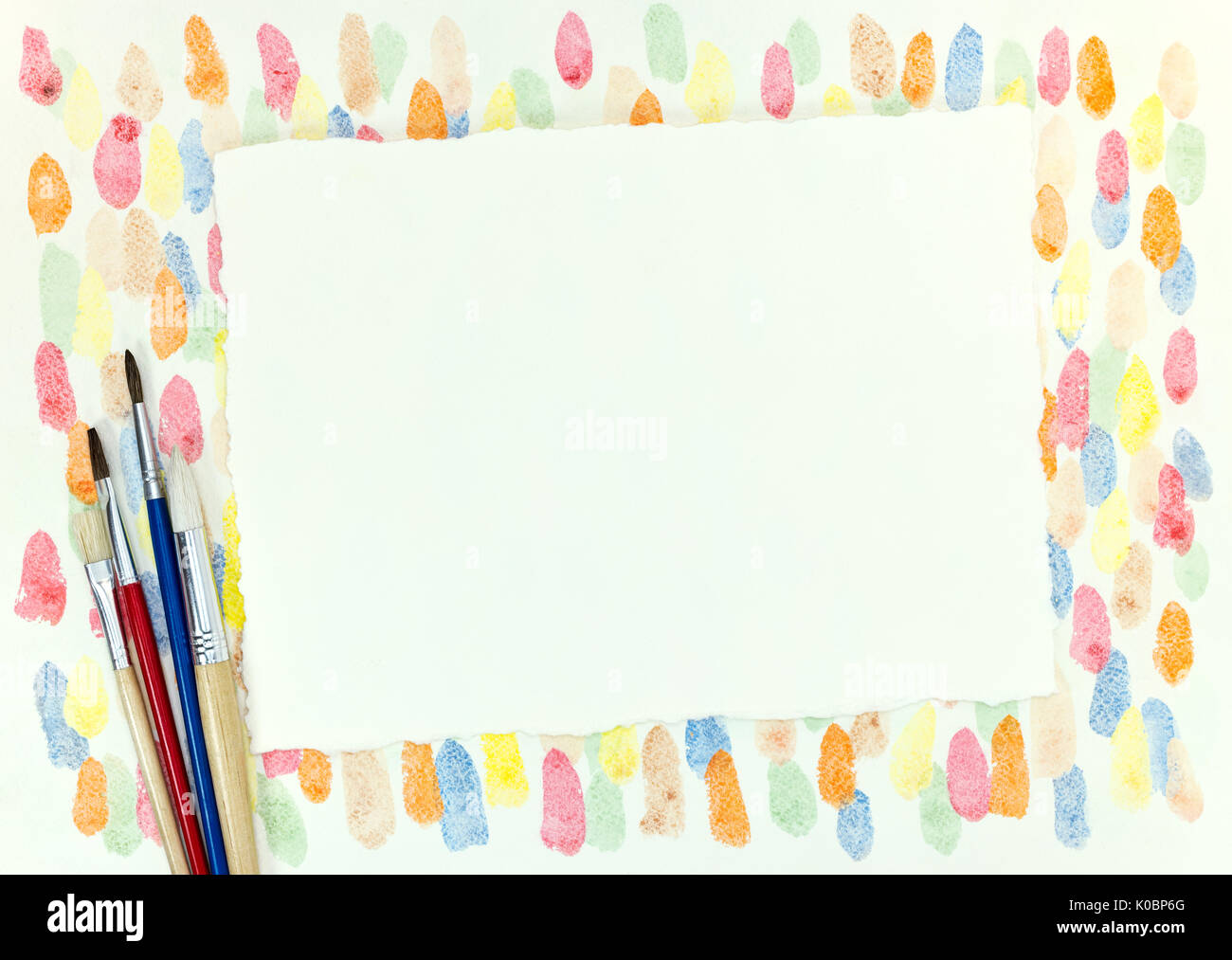 decorative chaotic colorful blobs texture and various paintbrushes with empty paper sheet Stock Photo