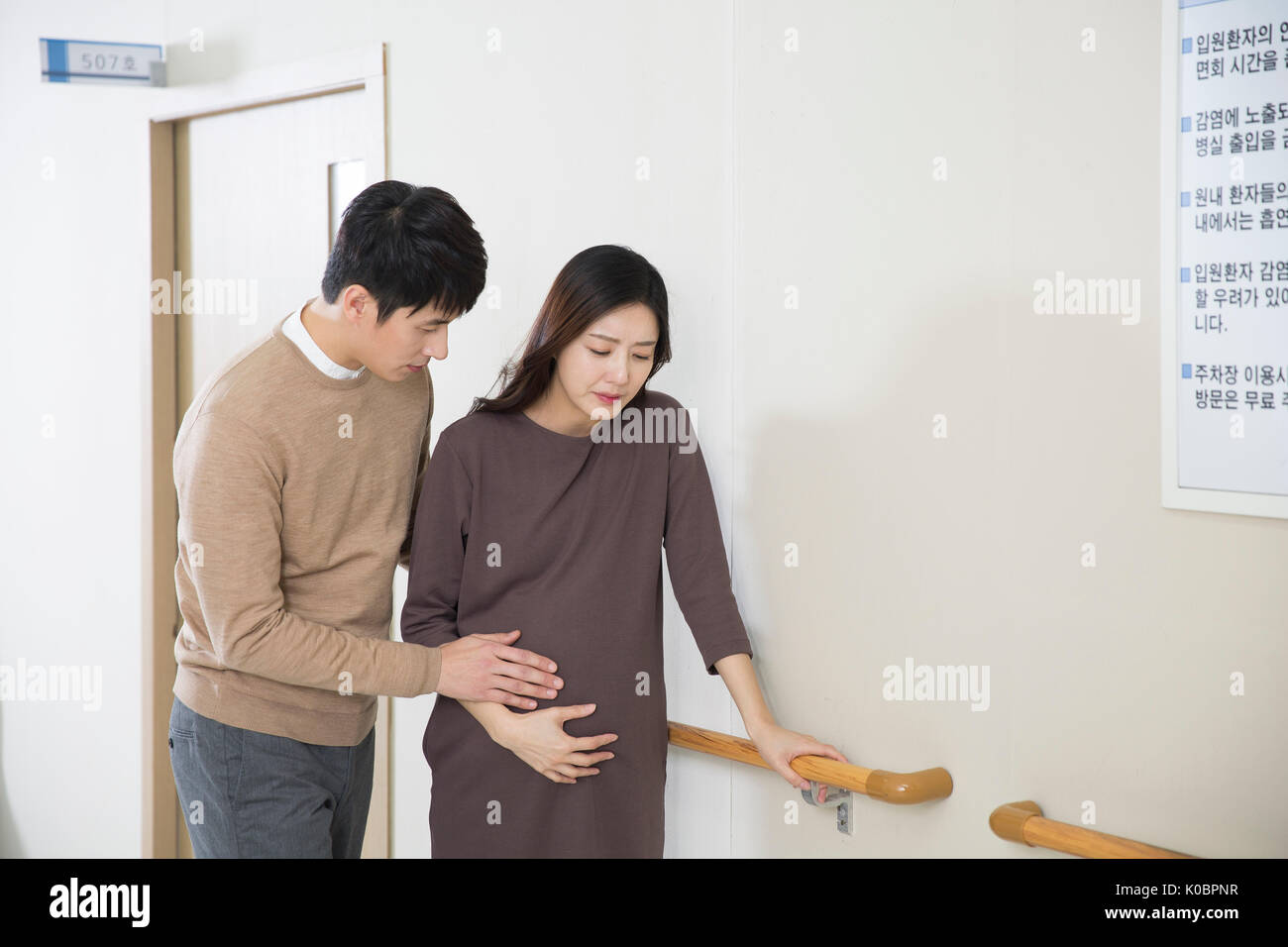 Pregnant wife feeling pain and her loving husband worried at hospital Stock Photo