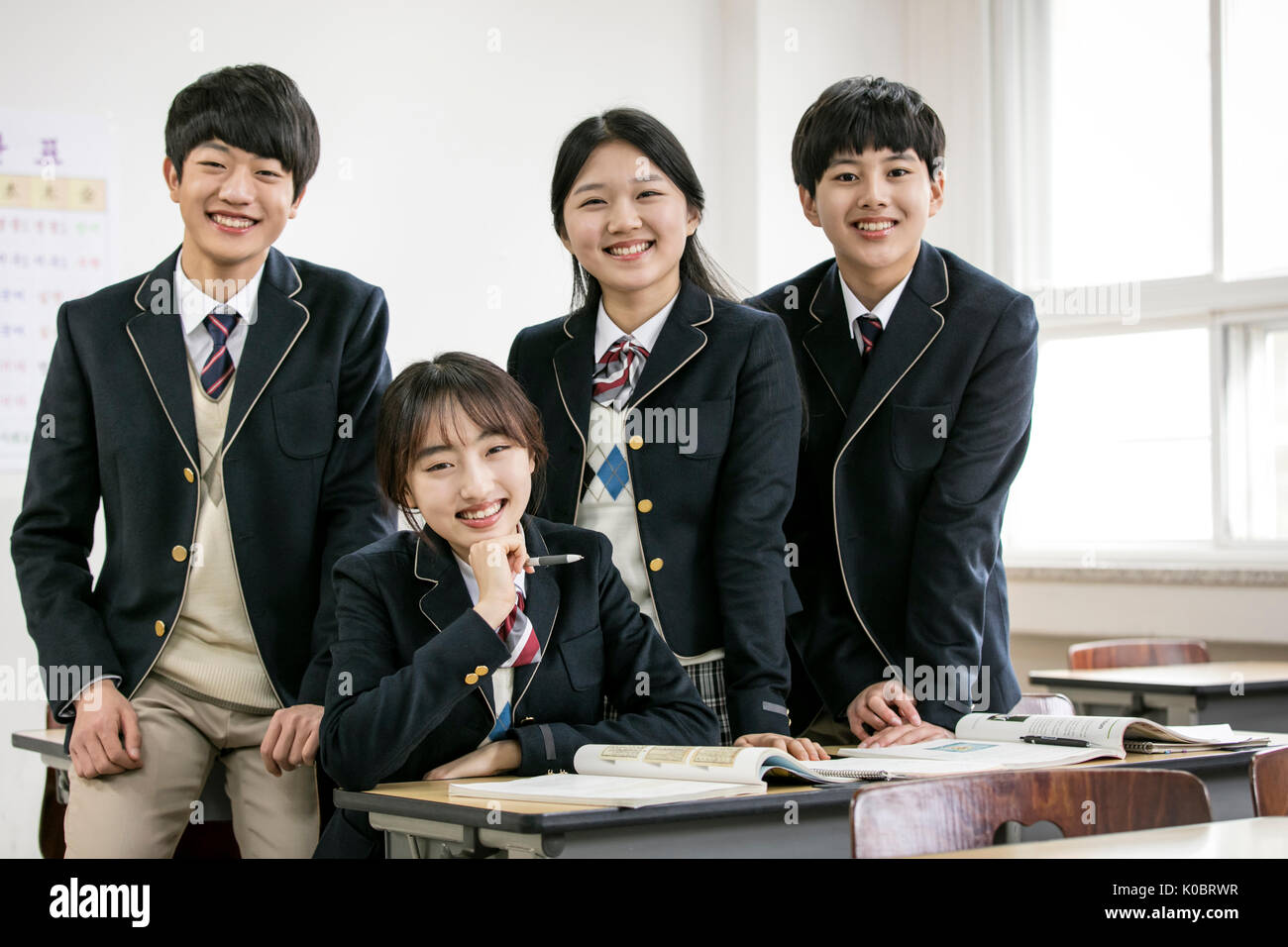 Four smiling school students posing in classroom Stock Photo