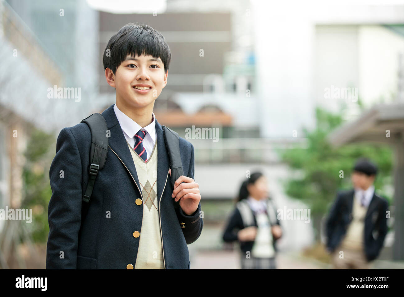 Smiling school boy standing against his school Stock Photo