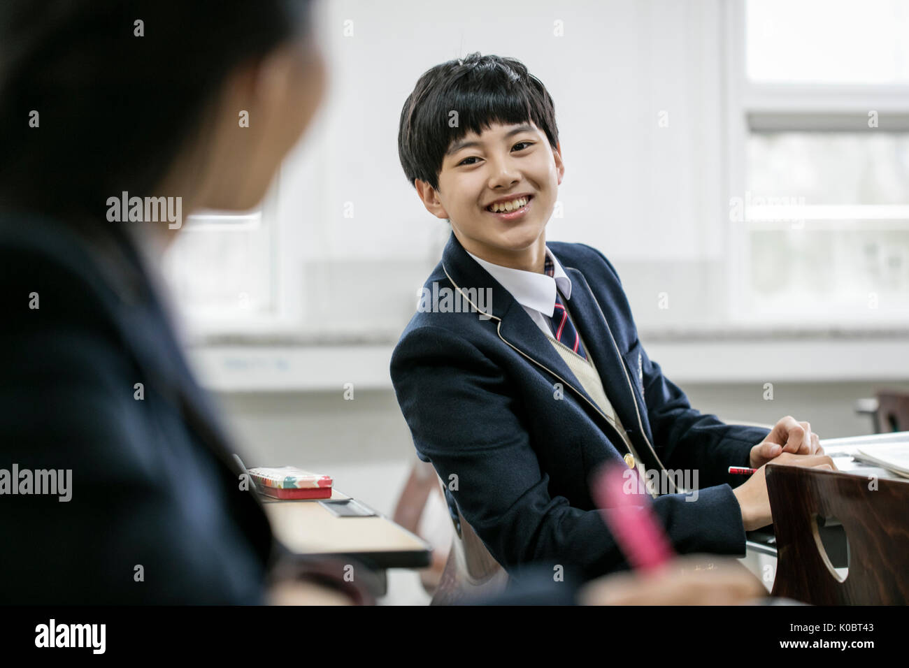 Portrait of school boy smiling at his friend in classroom Stock Photo