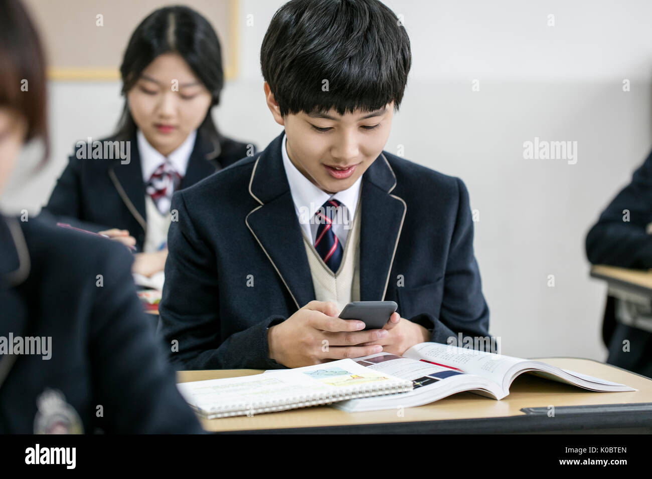 Portraitof school boy using smartphone in classroom Stock Photo