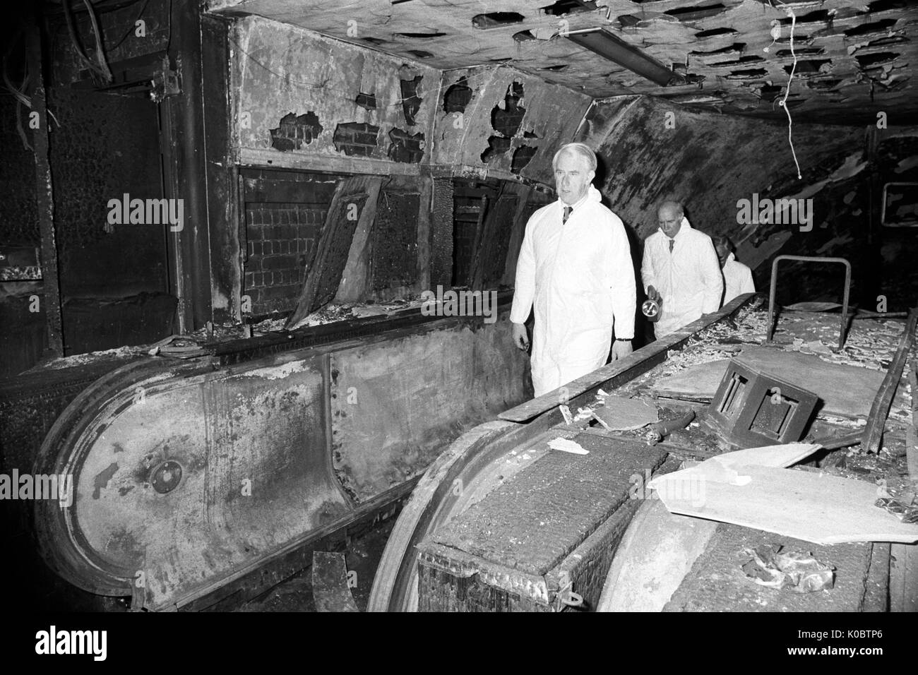 QC Desmond Fennell leads a team of men in white protective coats up the fire-damaged escalator at Stock Photo