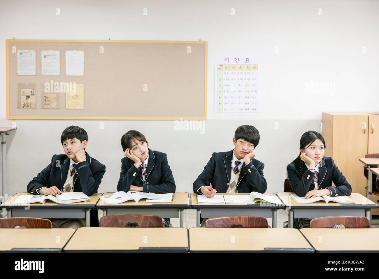 Four Korean school students worried sitting in classroom Stock Photo