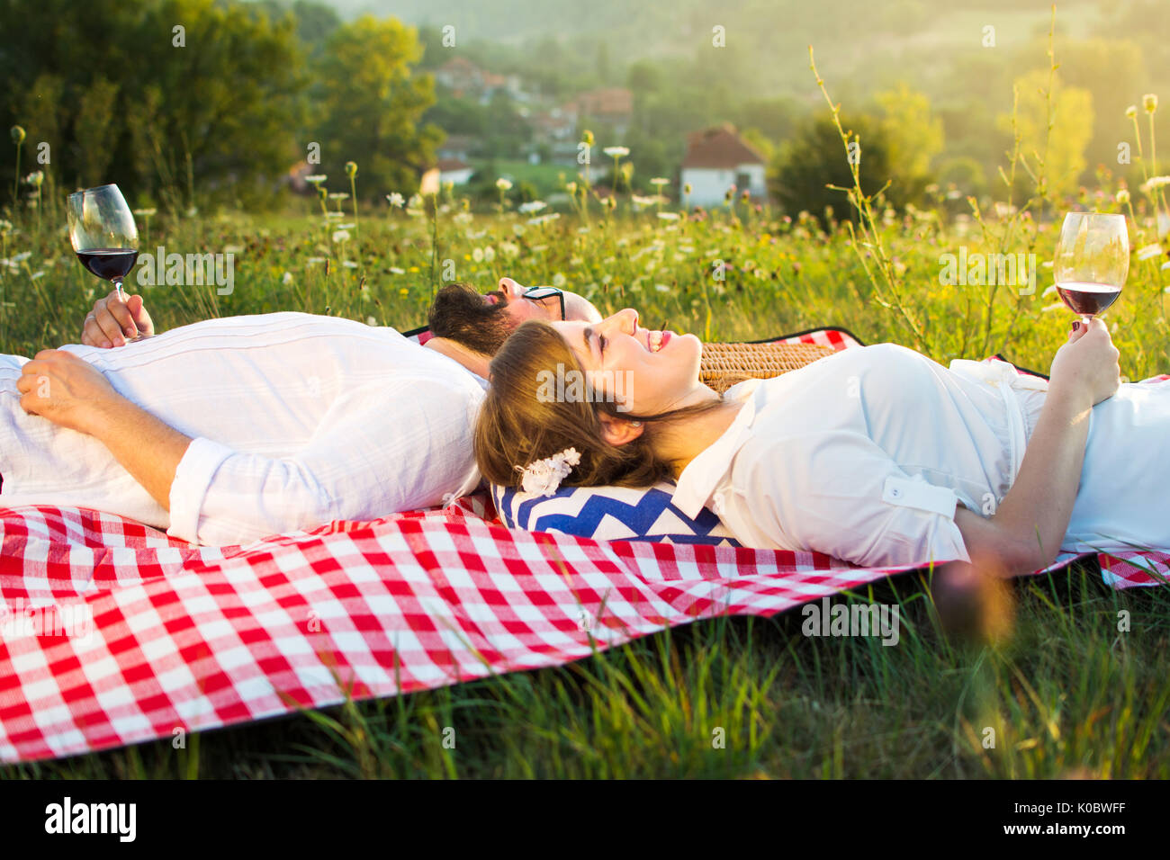 couple lying on a picnic blanket holding glass of wine Stock Photo